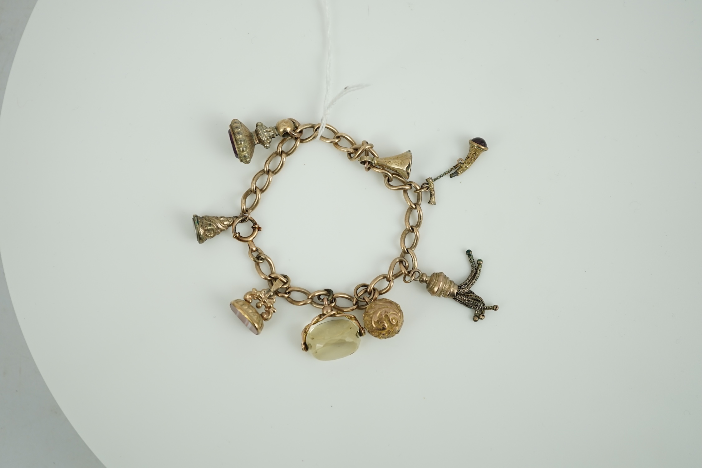 A 9ct gold charm bracelet, hung with eight assorted yellow metal overlaid charms, gross weight 33.4 grams.